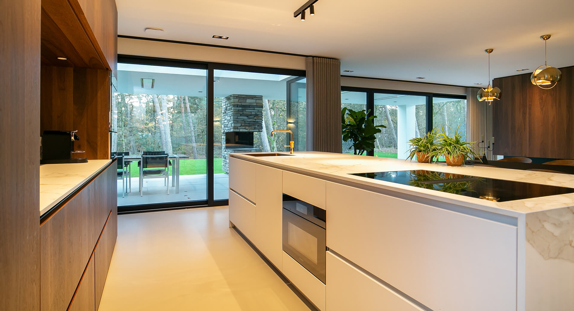 Moderne keuken met eiland en glazen schuifdeur uitzicht.