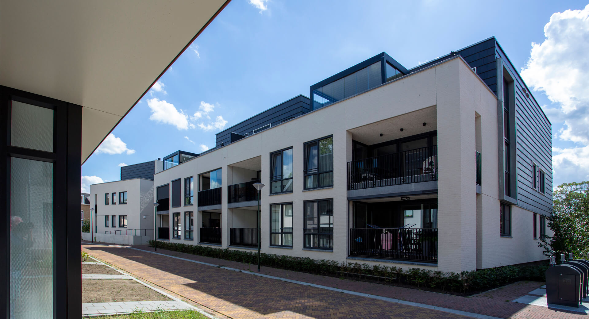 Modern appartementsgebouw met balkons en blauwe lucht.