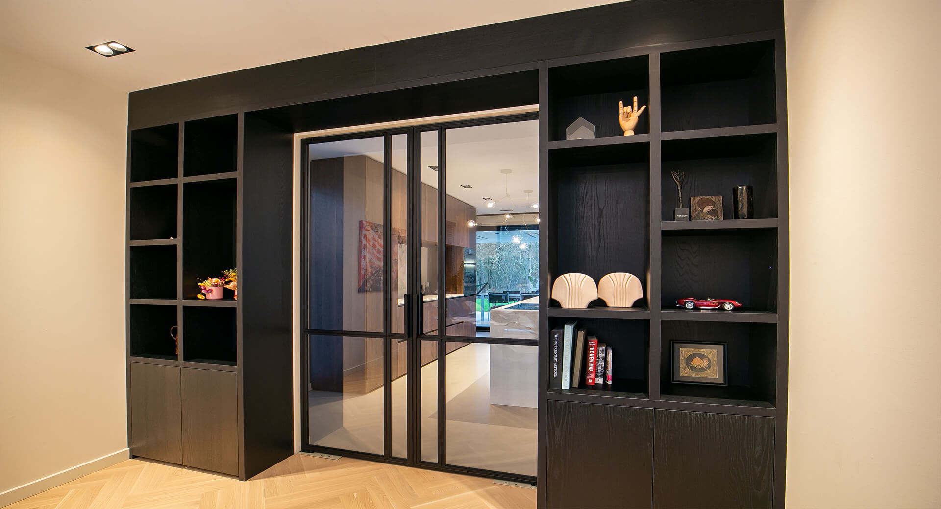Moderne woonruimte met open boekenkast en glazen deuren.